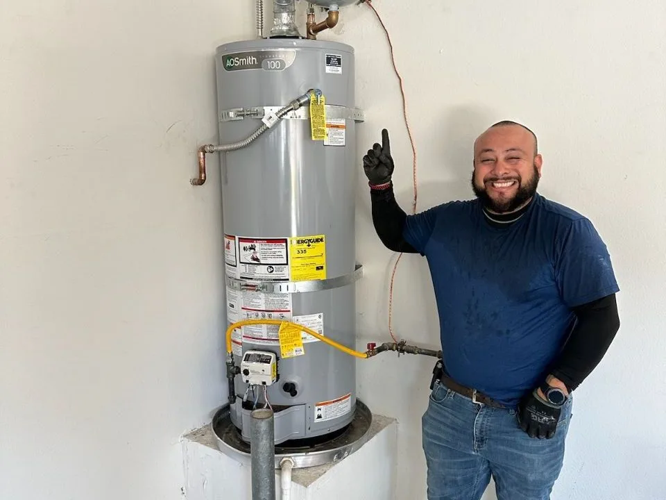 A DG Plumbing & Rooter technician beside a newly installed water heater.